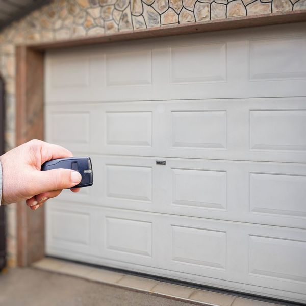 a person holding a cell phone in front of a door. features garage door services garage door repair garage door installation garage door spring repair new garage doors provided by Retrak Door Service.