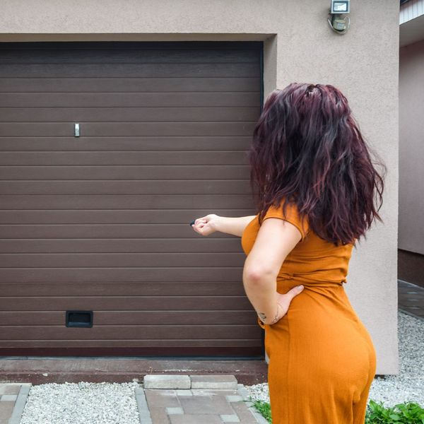 This scene from Lakewood, CO shows a man holding a remote control in front of a vehicle. with features such as garage door services garage door repair garage door installation garage door spring repair new garage doors.