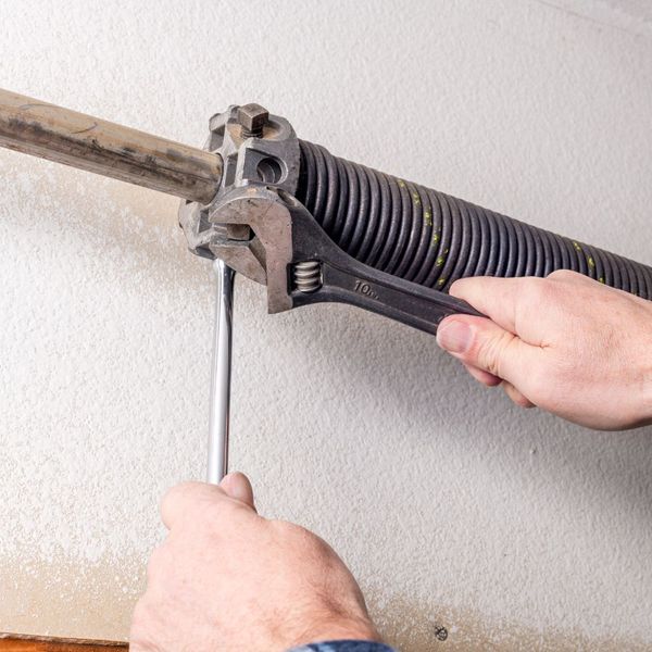 A person holding a pair of scissors to a wall. showcasing features like garage door services garage door repair garage door installation garage door spring repair.