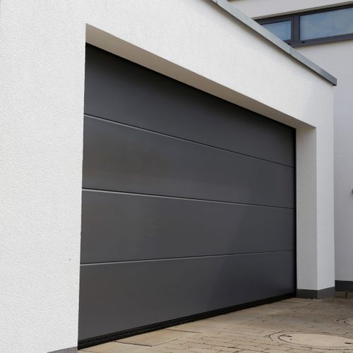 This scene from Lakewood, CO shows a large white building with a black door. with features such as garage door services garage door repair garage door installation.