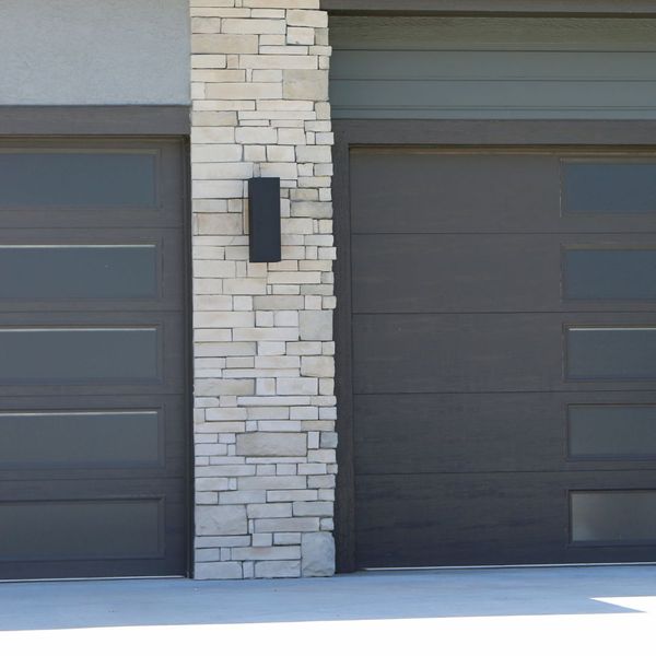 This scene from Lakewood, CO shows a brick building with a door open and a brick wall. with features such as garage door services garage door repair garage door installation garage door spring repair new garage doors.