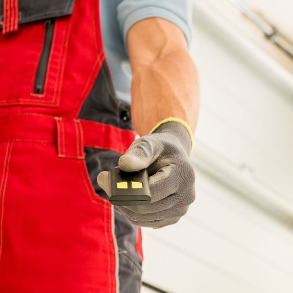 a man in a red jacket is using a red and white hand. features garage door services garage door repair garage door installation garage door spring repair new garage doors emergency garage door service provided by Retrak Door Service.