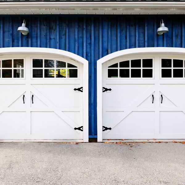 a white door leading to a barn with a blue door. features garage door services garage door repair garage door installation garage door spring repair new garage doors provided by Retrak Door Service.