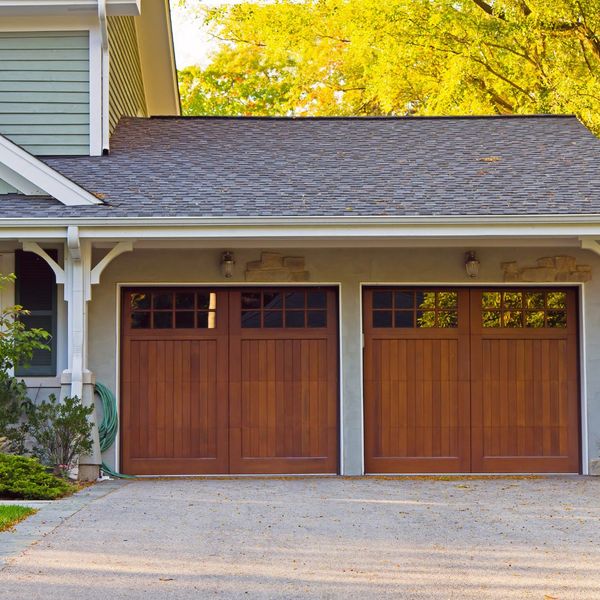 This scene from Lakewood, CO shows a house with a wooden door and a white house. with features such as garage door services garage door repair garage door installation garage door spring repair.